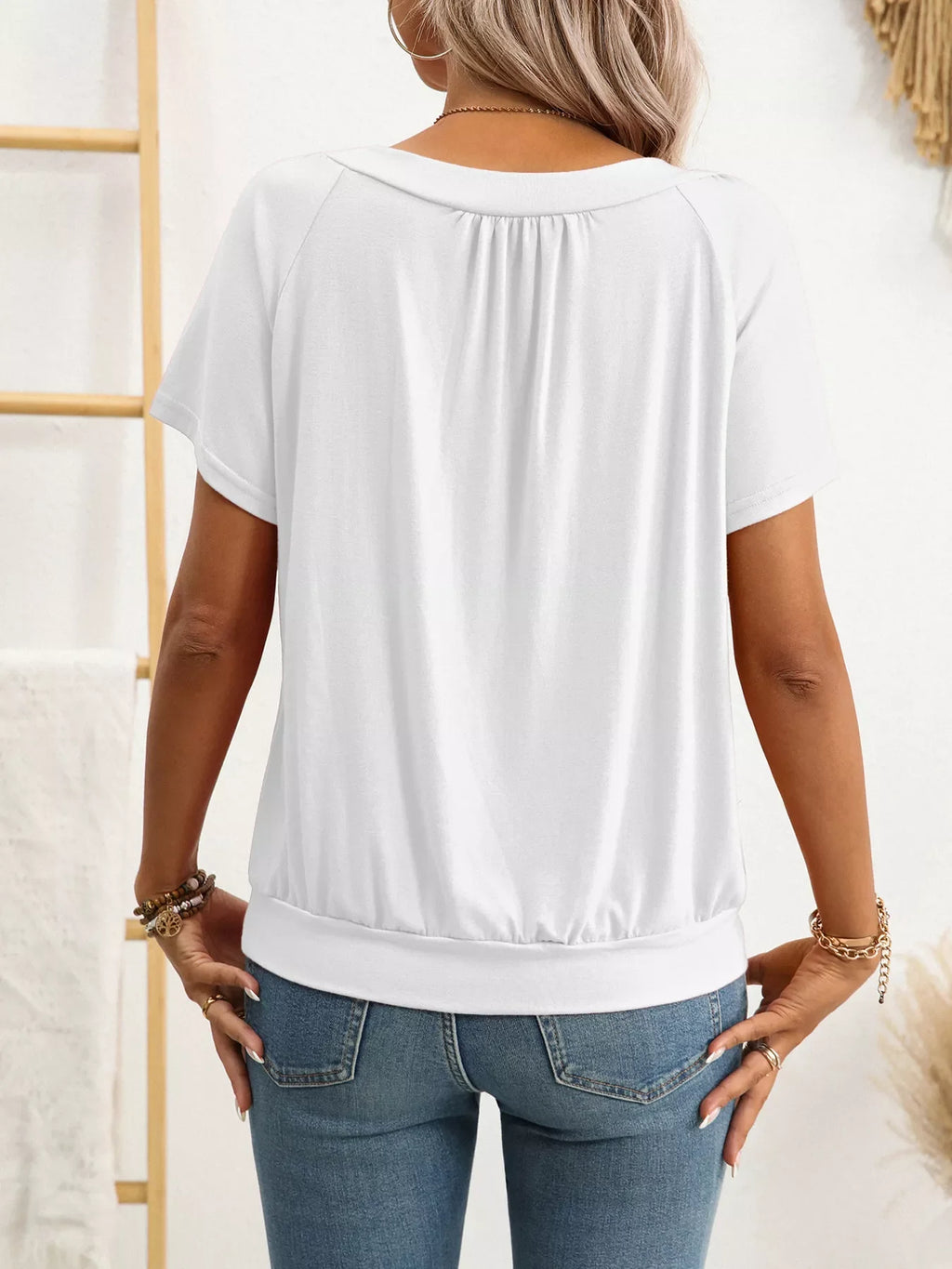 Person wearing a white blouse and blue jeans with a neutral background