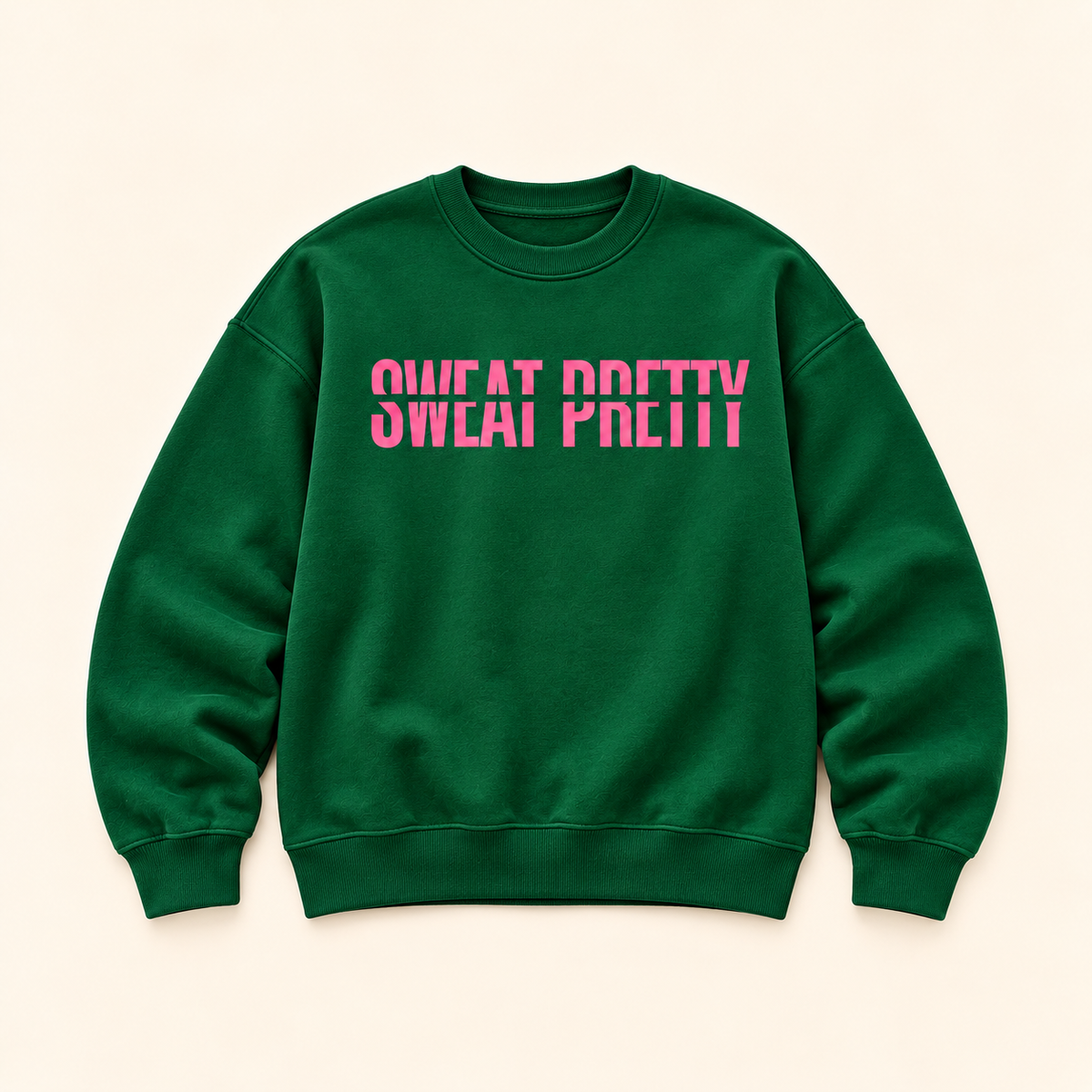 A dark green crewneck sweatshirt with the phrase 'SWEAT PRETTY' printed across the chest in a vibrant pink stencil font, displayed flat against a light beige background.