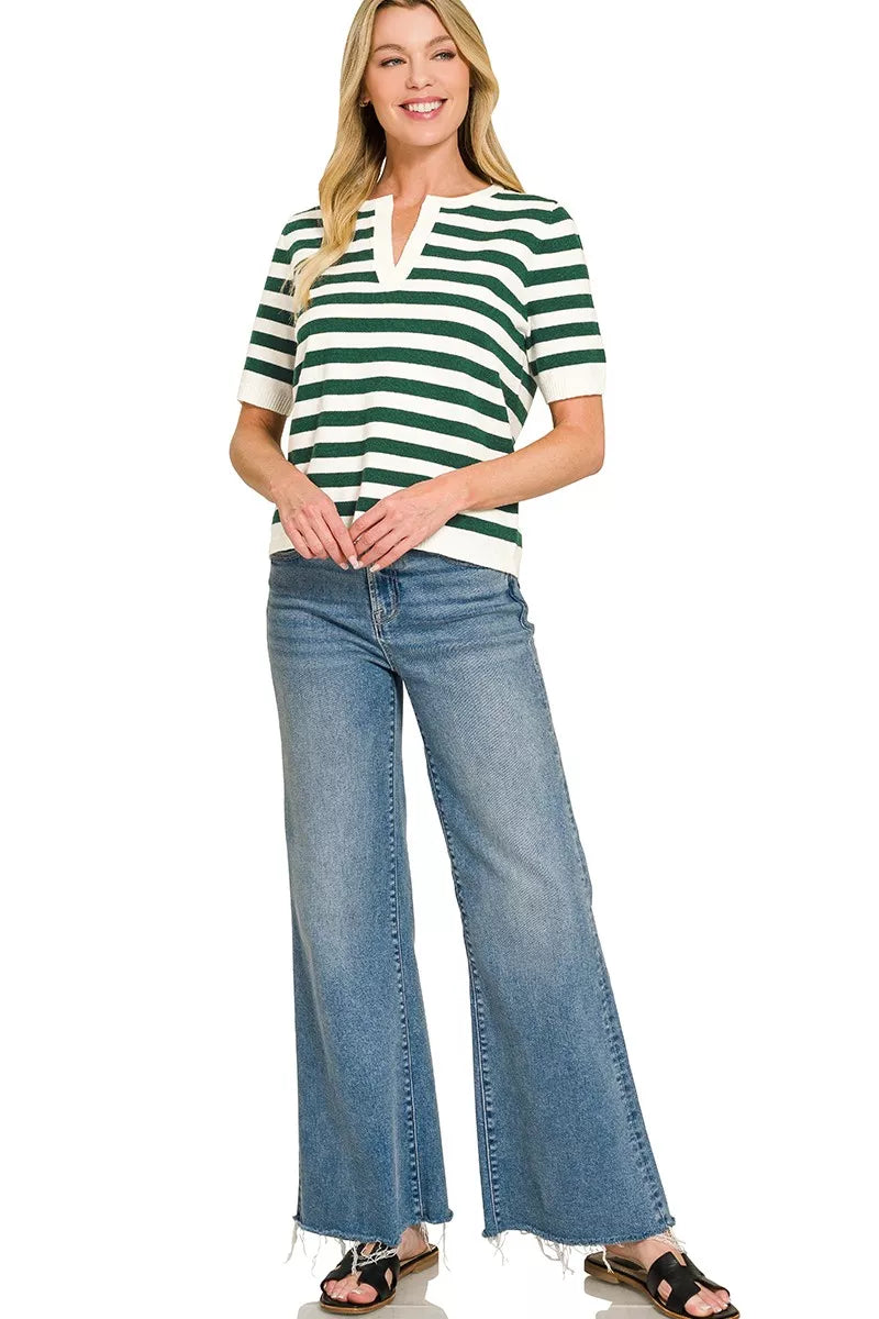 Woman wearing a green and white striped shirt and blue jeans on a white background