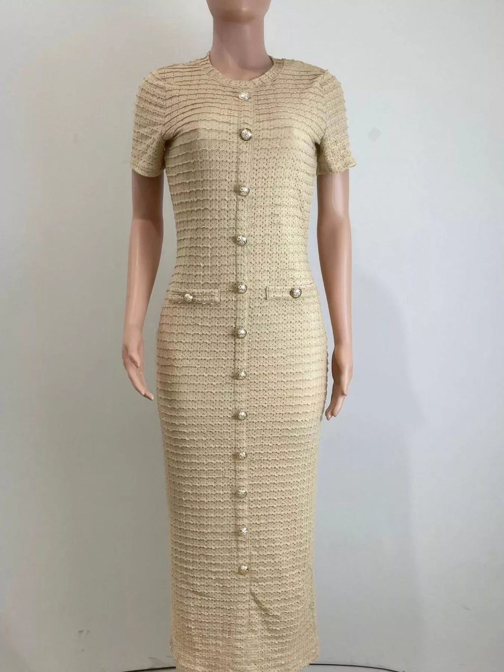 Mannequin wearing a beige textured dress with button details on a plain background