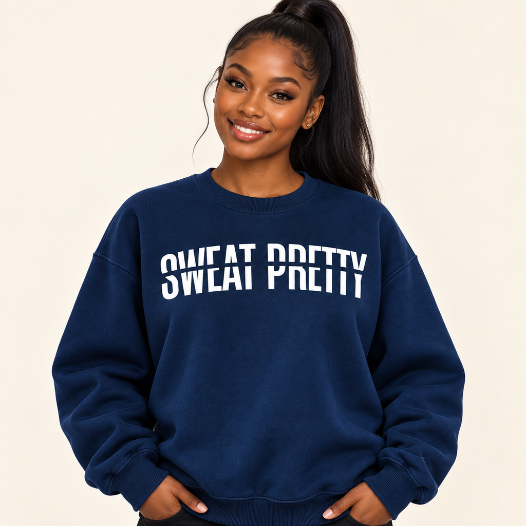A woman with a high ponytail wearing a navy blue sweatshirt with 'SWEAT PRETTY' printed in white across the chest, posed against a solid light beige background.