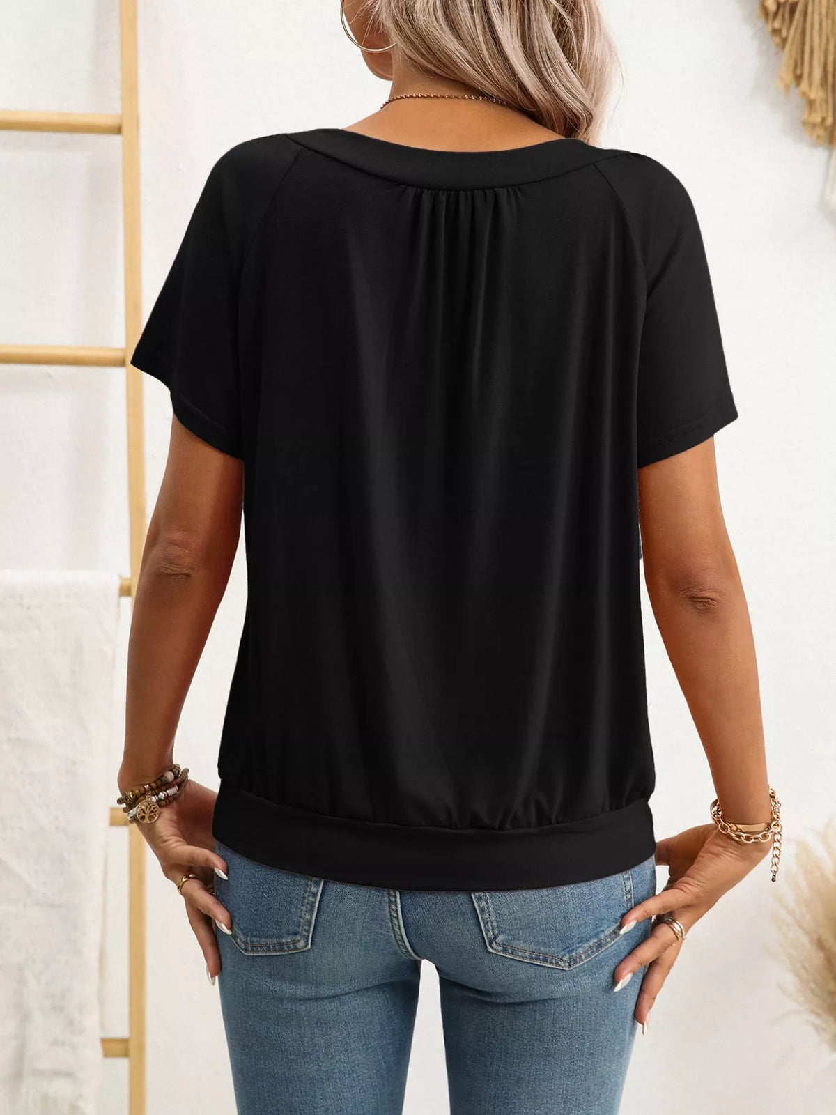 Person wearing a black top and blue jeans with a white background