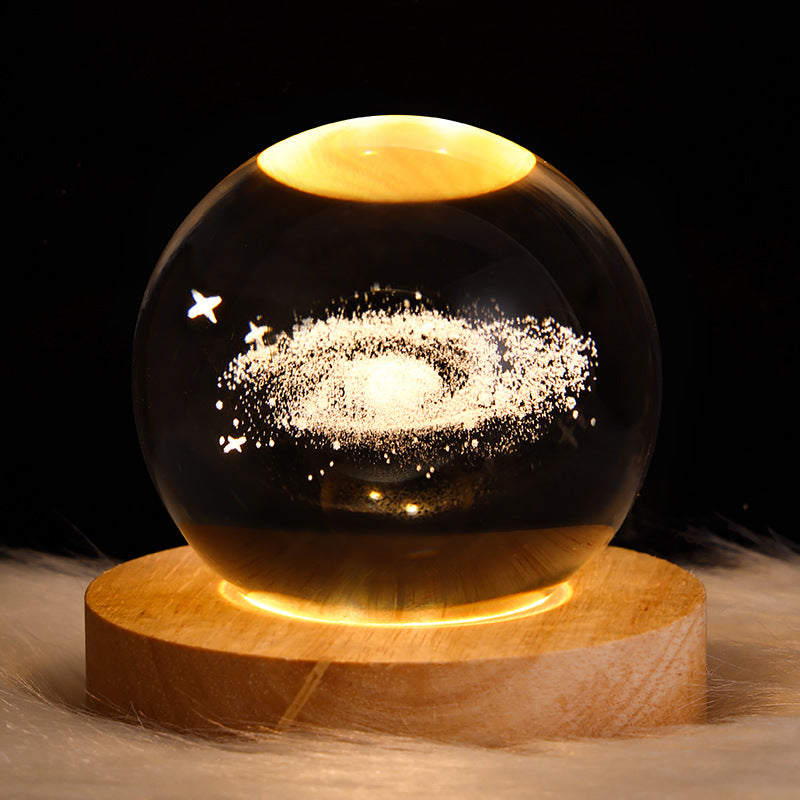 Glass sphere with starry night design on a wooden base against a dark background