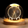 Glass sphere with a Ferris wheel design on a wooden base against a dark background