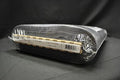 A roll of black fabric or material wrapped in clear plastic packaging, photographed on a dark fabric background.
