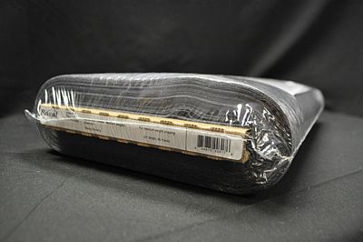 A roll of black fabric or material wrapped in clear plastic packaging, photographed on a dark fabric background.