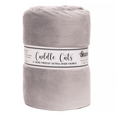 A rolled-up light gray plush fabric blanket with a paper label reading 'Cuddle Cuts' and 'Shampoon' on a white background.