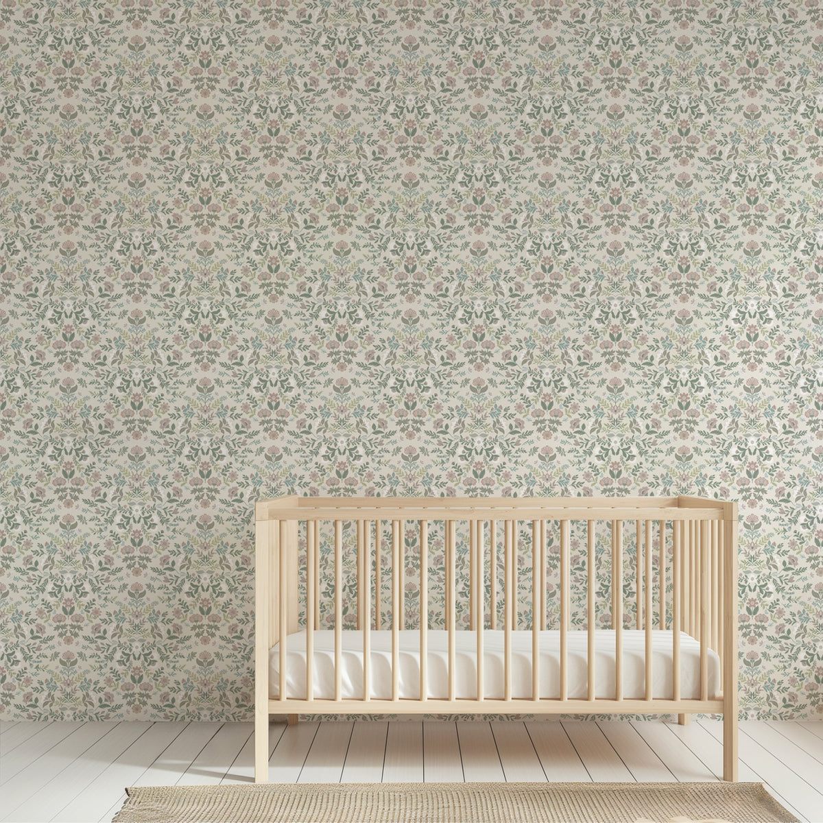 A light natural wood crib with a white mattress placed in front of a wall covered in an intricate, repeating botanical damask wallpaper pattern.