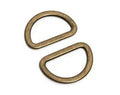 Two antique bronze metal D-rings with a textured finish, arranged diagonally on a plain white background.