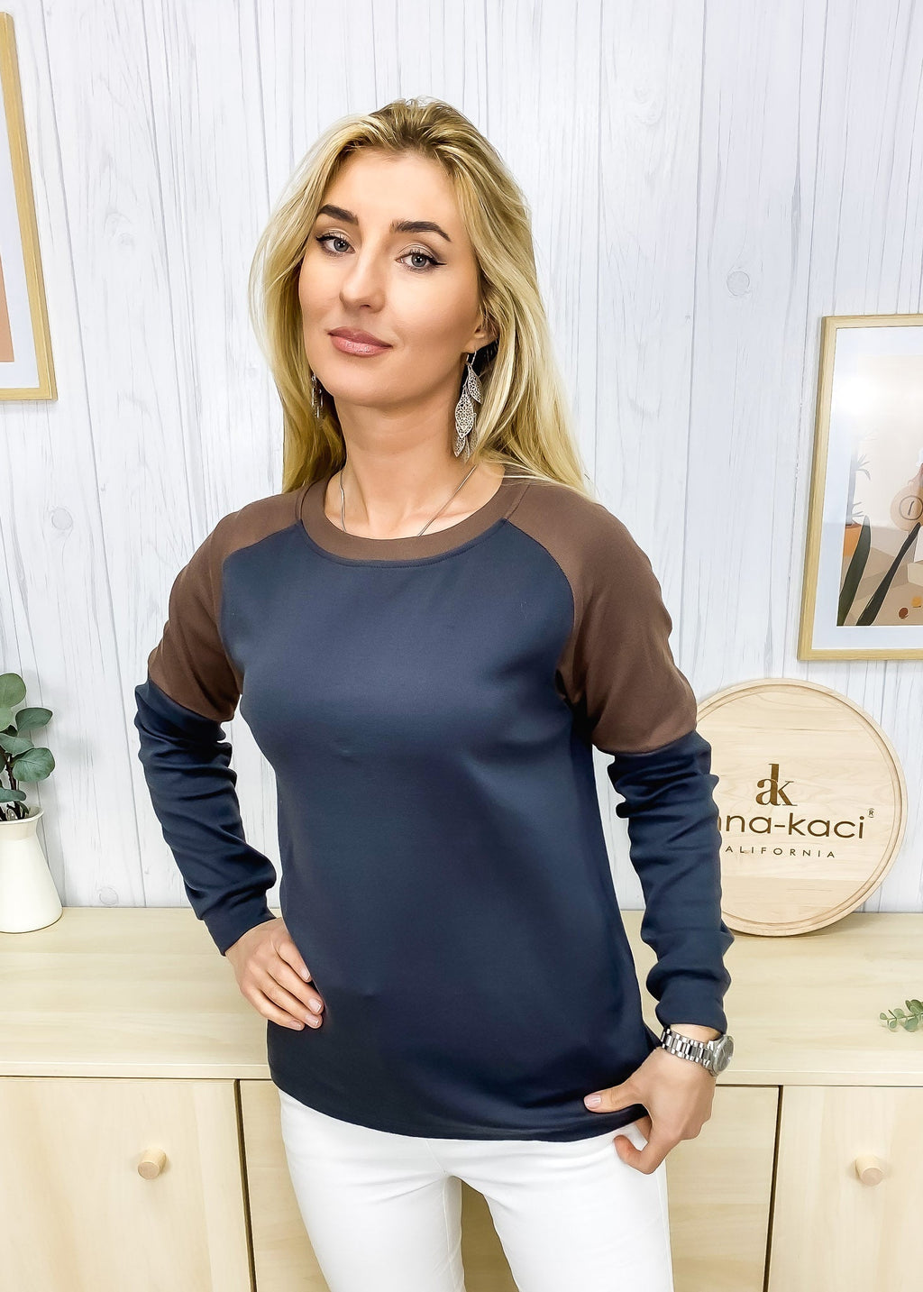 Woman wearing a navy and brown long-sleeve top in a home setting with decorative elements.
