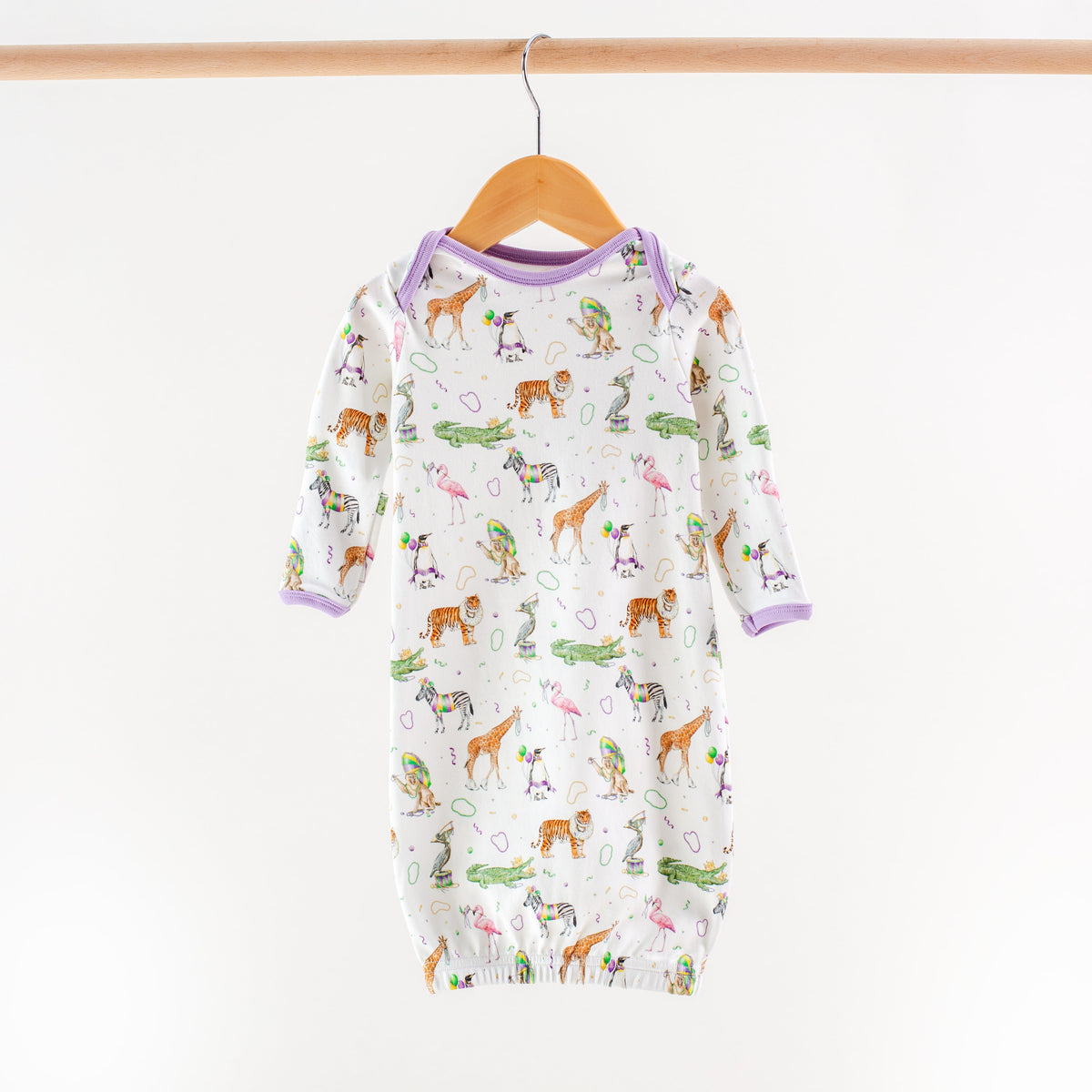 Baby onesie with animal pattern on a wooden hanger against a white background