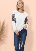 Woman wearing a white sweater with leopard print sleeves against a beige background