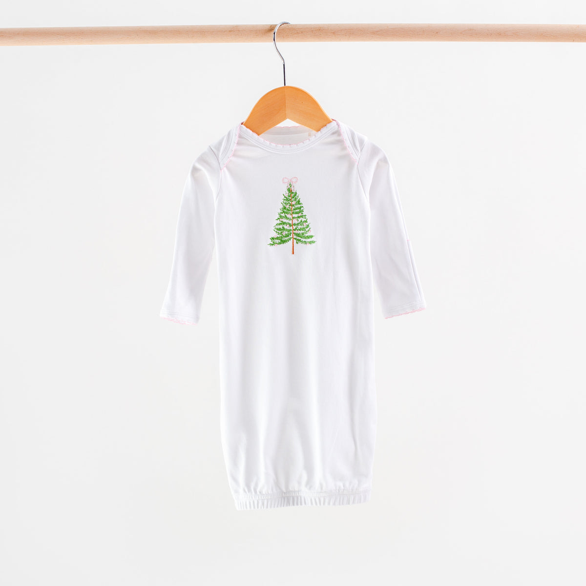 White long-sleeve shirt with a green tree design on a wooden hanger against a white background