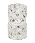A folded plush faux fur blanket with a white and gray mottled pattern, wrapped in a white paper band that reads 'Cuddle Cuts'.