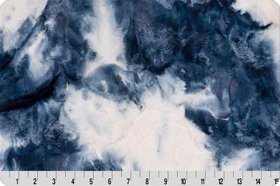A close-up of a marbled fabric or material sample with swirling dark blue, navy, and white areas, shown with a measurement ruler along the bottom edge.