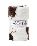 A rolled plush fabric with a brown and white cow-print pattern, wrapped in a white paper band labeled 'Cuddle Cuts'.
