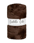A rolled-up plush faux fur fabric in dark brown with a white paper label wrapped around the middle that reads 'Cuddle Cats'.