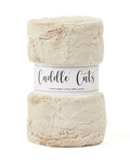 A folded plush faux fur fabric in a light oatmeal beige color, wrapped in a white paper band that reads 'Cuddle Cuts'.