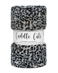 A folded plush faux-fur fabric with a black and white leopard print pattern, wrapped in a white paper band that reads 'Cuddle Cuts'.