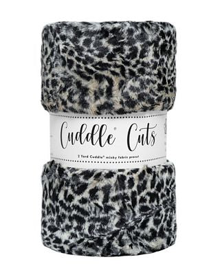 A folded plush faux-fur fabric with a black and white leopard print pattern, wrapped in a white paper band that reads 'Cuddle Cuts'.