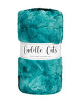 A folded plush fabric in a teal turquoise color, wrapped with a white paper band that reads 'Cuddle Cuts'.