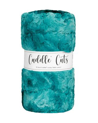 A folded plush fabric in a teal turquoise color, wrapped with a white paper band that reads 'Cuddle Cuts'.