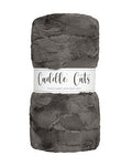 A folded plush faux-fur fabric in dark gray with a white paper label band reading 'Cuddle Cats' on a plain white background.