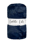 A folded navy blue faux fur plush fabric with a white paper label that reads 'Cuddle Cuts' on a plain white background.