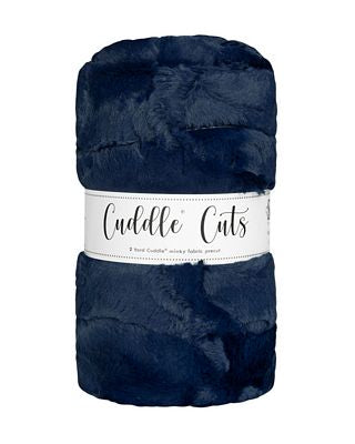 A folded navy blue faux fur plush fabric with a white paper label that reads 'Cuddle Cuts' on a plain white background.