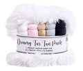 A packaged bundle of faux fur blankets labeled 'Dreamy Fur Fun Pack,' featuring fluffy white faux fur with folded pastel and dark gray/charcoal pieces visible behind a white paper band.