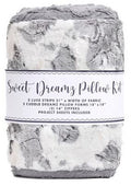 A folded plush throw blanket in a gray and white marbled pattern, wrapped with a paper label that reads 'Sweet Dreamz Pillow Kit' and lists included fabric strips, pillow forms, and zipper sheets.