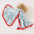 Folded baby blanket with red trim and floral pattern on a beige background