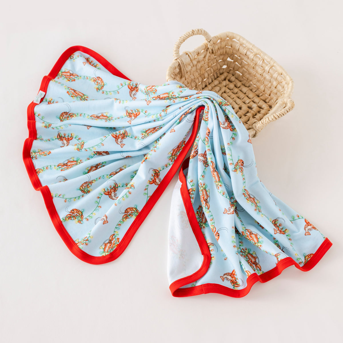 Folded baby blanket with red trim and floral pattern on a beige background
