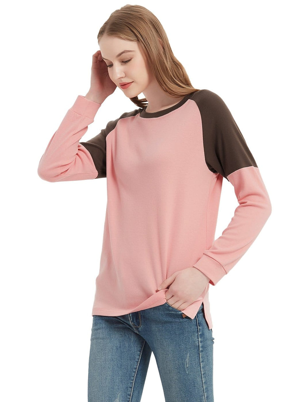 Woman wearing a pink and brown long-sleeve top with blue jeans on a white background