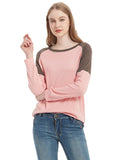 Woman wearing a pink and brown long-sleeve top with blue jeans on a white background