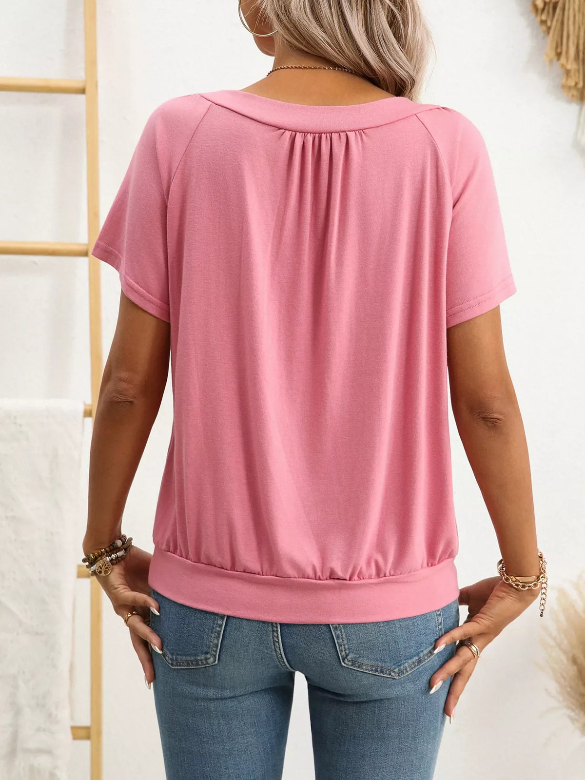 Person wearing a pink top and blue jeans with a white background