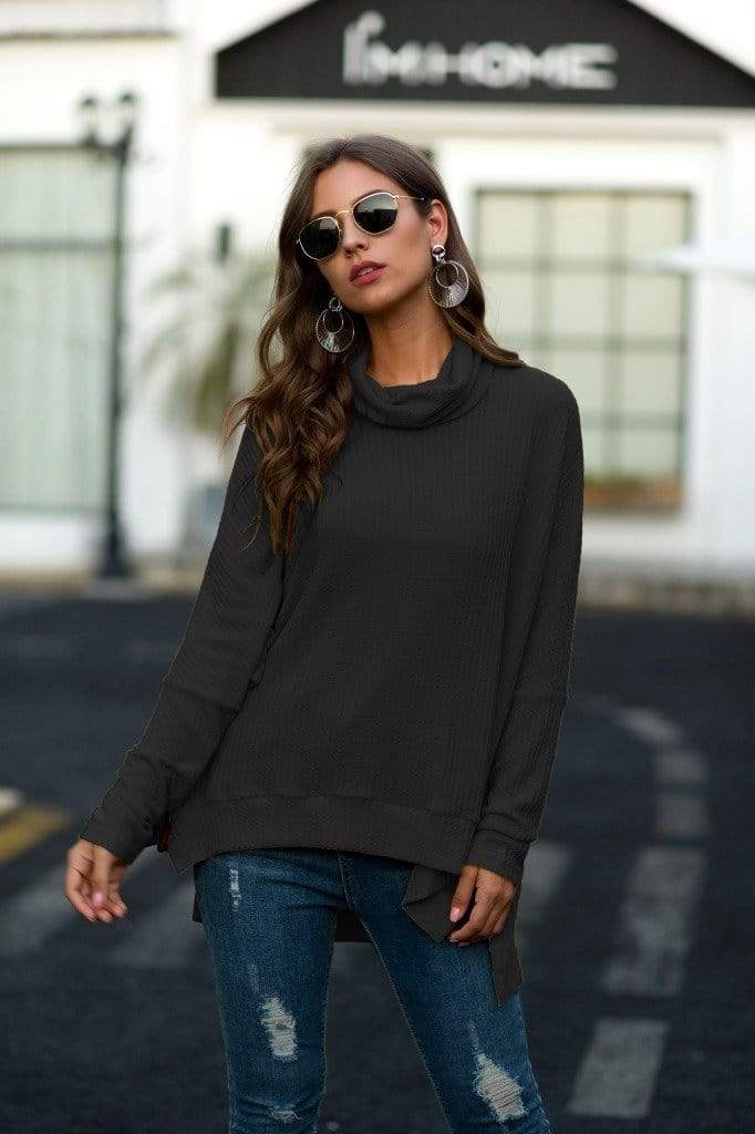 Woman wearing a black sweater and blue jeans in an urban setting
