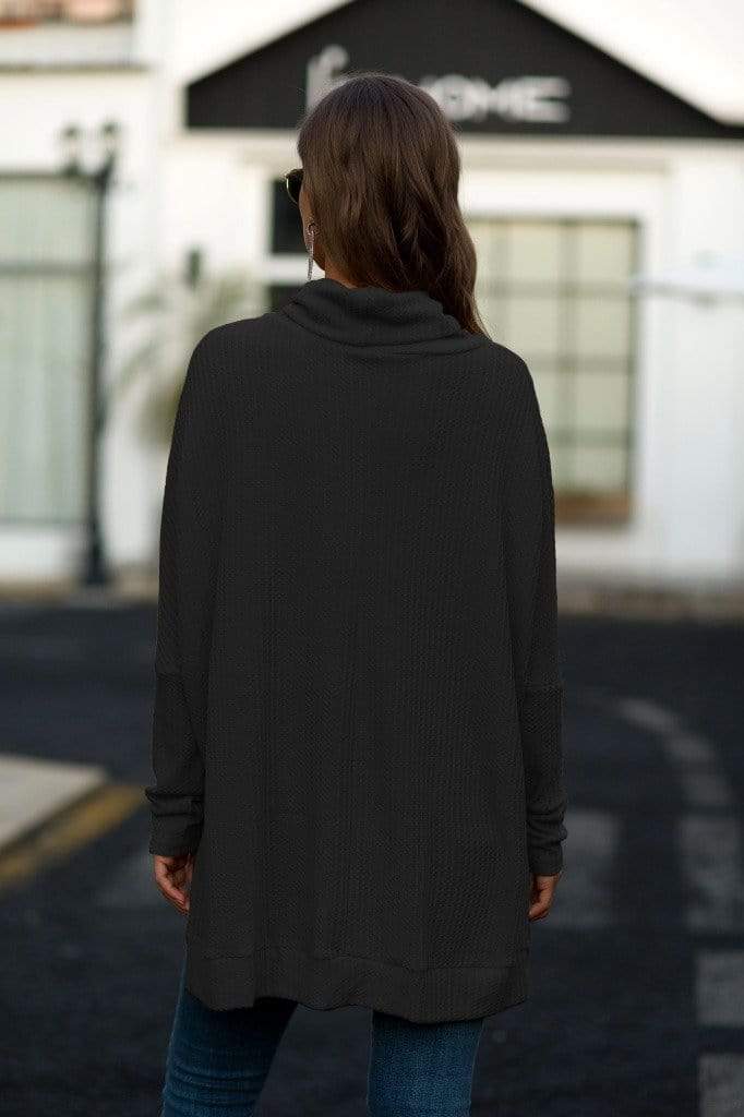 Person wearing a black long-sleeve top with a blurred background