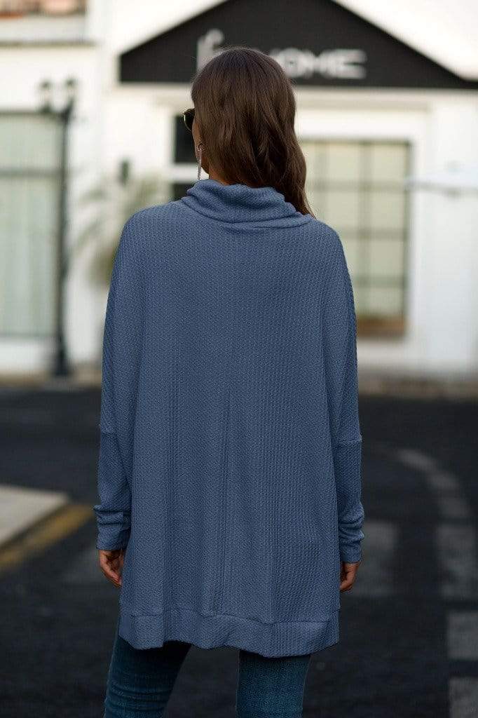 Person wearing a blue sweater with a blurred background