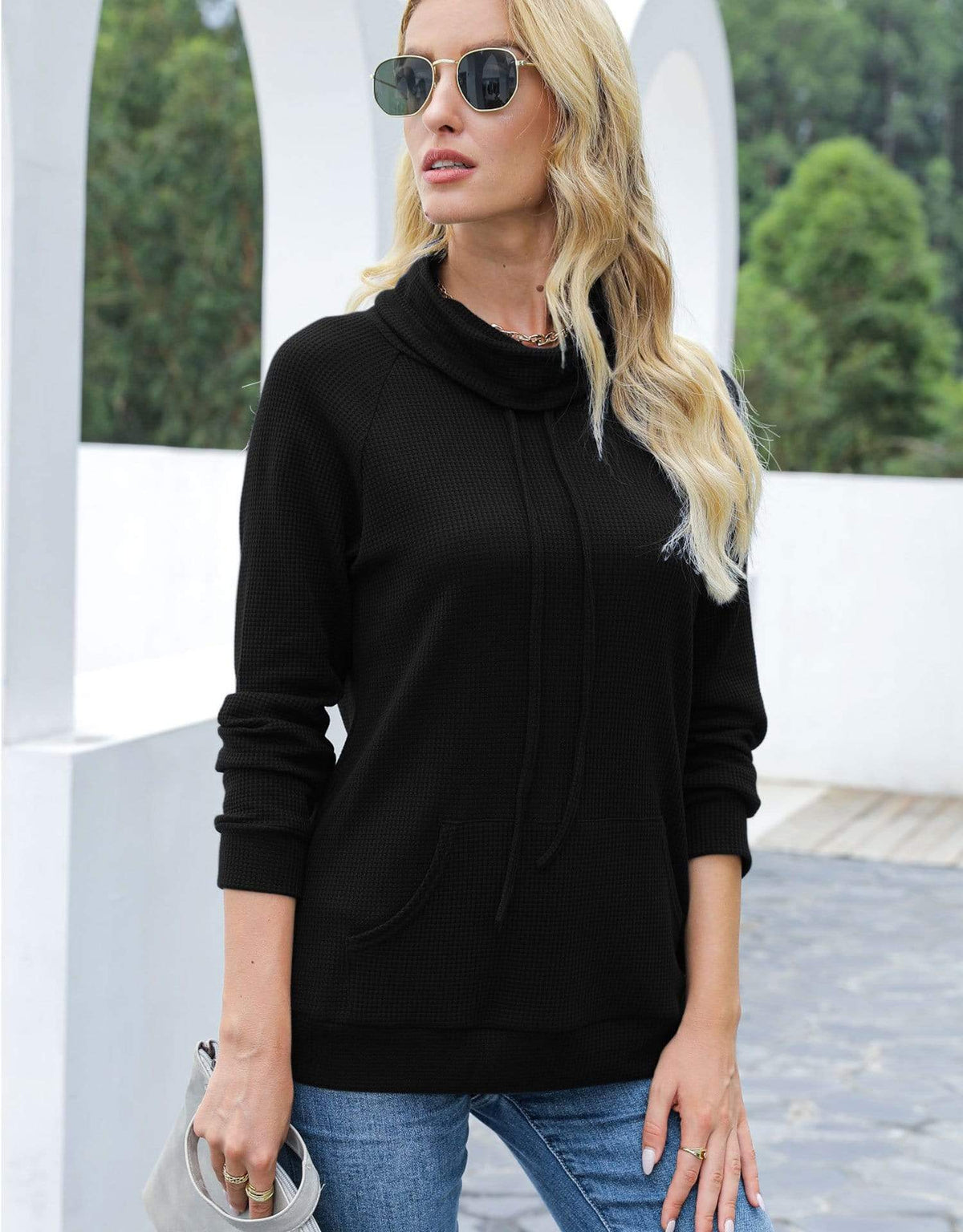 Woman wearing a black cowl-neck sweater and sunglasses outdoors.