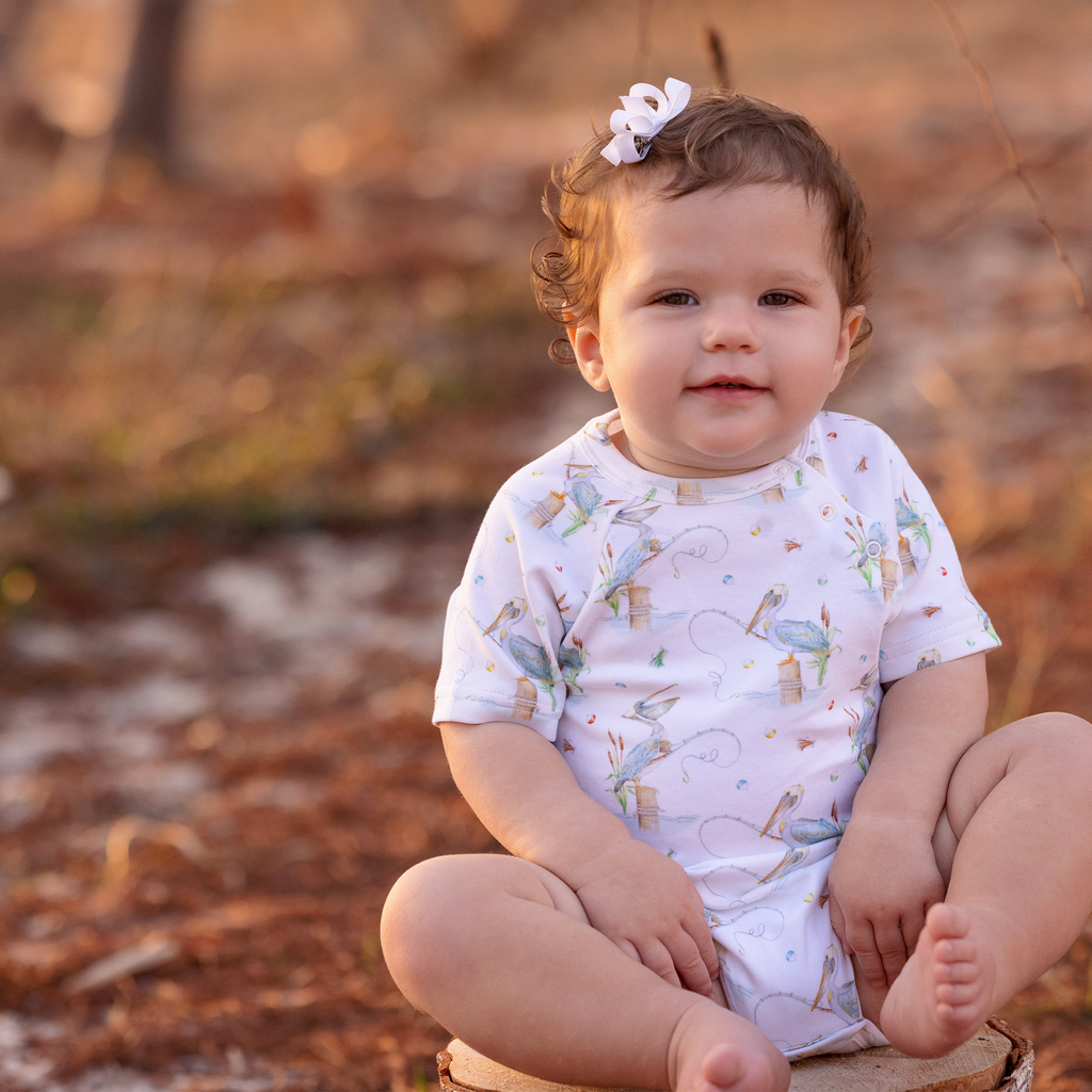 Baby sitting outdoors with a blurred natural background